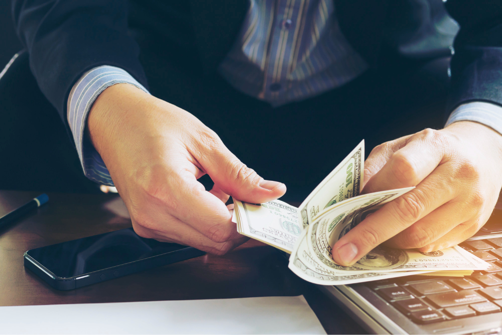 Businessman counting cash at desk.