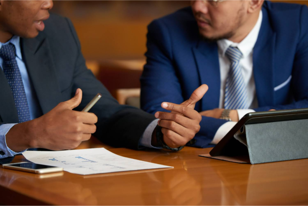 Two professionals in suits discussing financial documents, representing estate tax planning consultations.