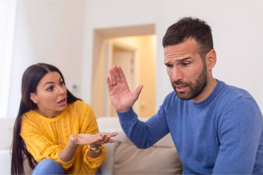 A couple engaged in an intense discussion, with the woman gesturing while the man appears defensive or frustrated.