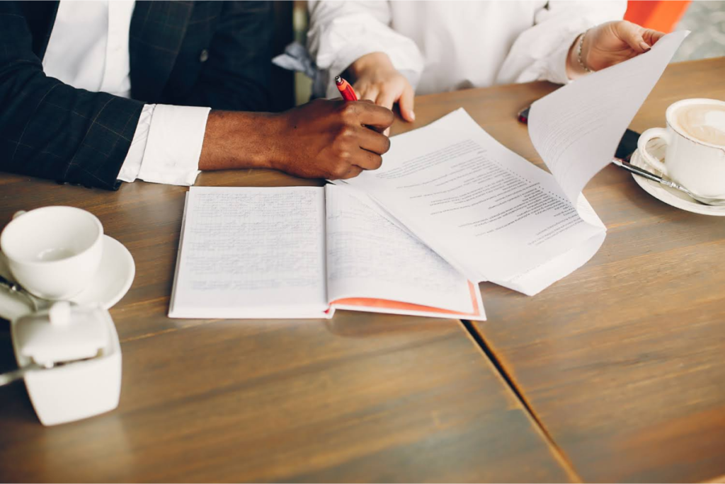 Two individuals reviewing and signing legal documents at a table, representing the process of finalizing estate plans.