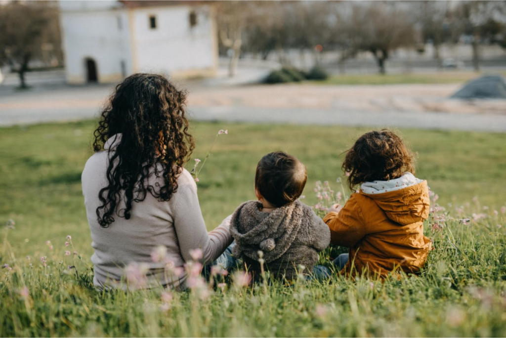 A woman with two kids sitting outdoors