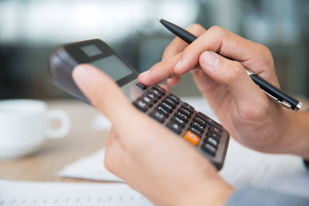 Close-up of a person using a calculator and holding a pen, representing financial calculations related to Texas estate tax.